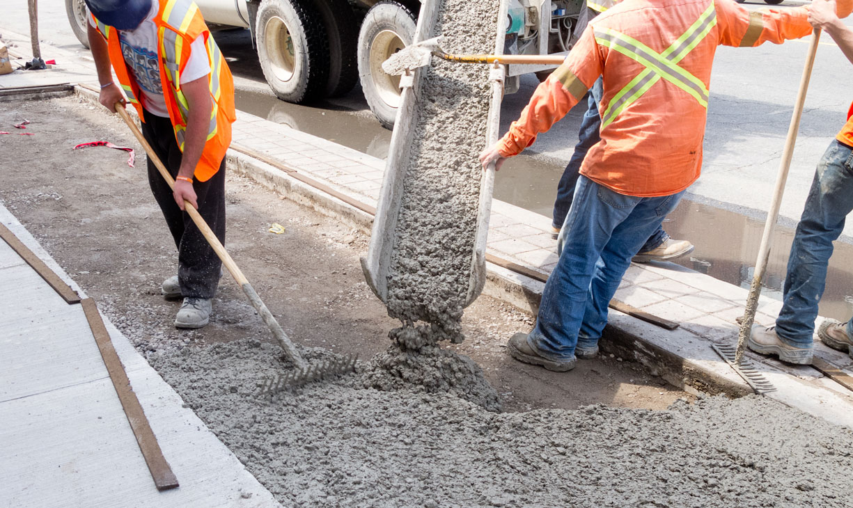 Bonded construction crew pouring cement in a public right of way