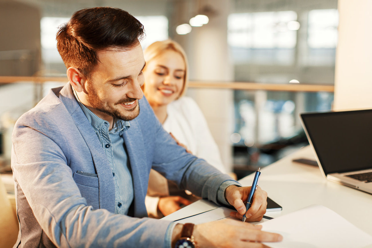 Man signing a physical document at a bank with a STAMP bond